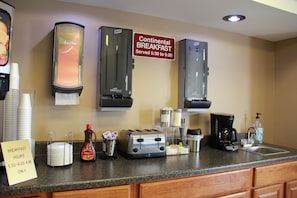 A breakfast area with a sign indicating Continental Breakfast is served from 5:30 to 9:00 AM.