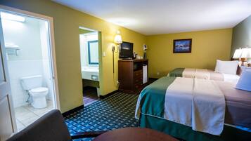 Une chambre d’hôtel comprenant un lit, un bureau, une chaise, une télévision, une salle de bain avec des toilettes et un miroir.