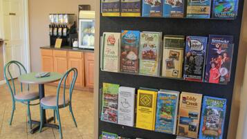 Un tablón de anuncios con folletos de viajes y una estación de café al fondo.