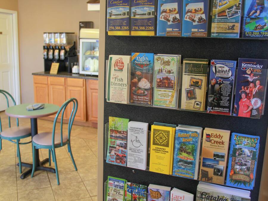Un tablón de anuncios con folletos de viajes y una estación de café al fondo.