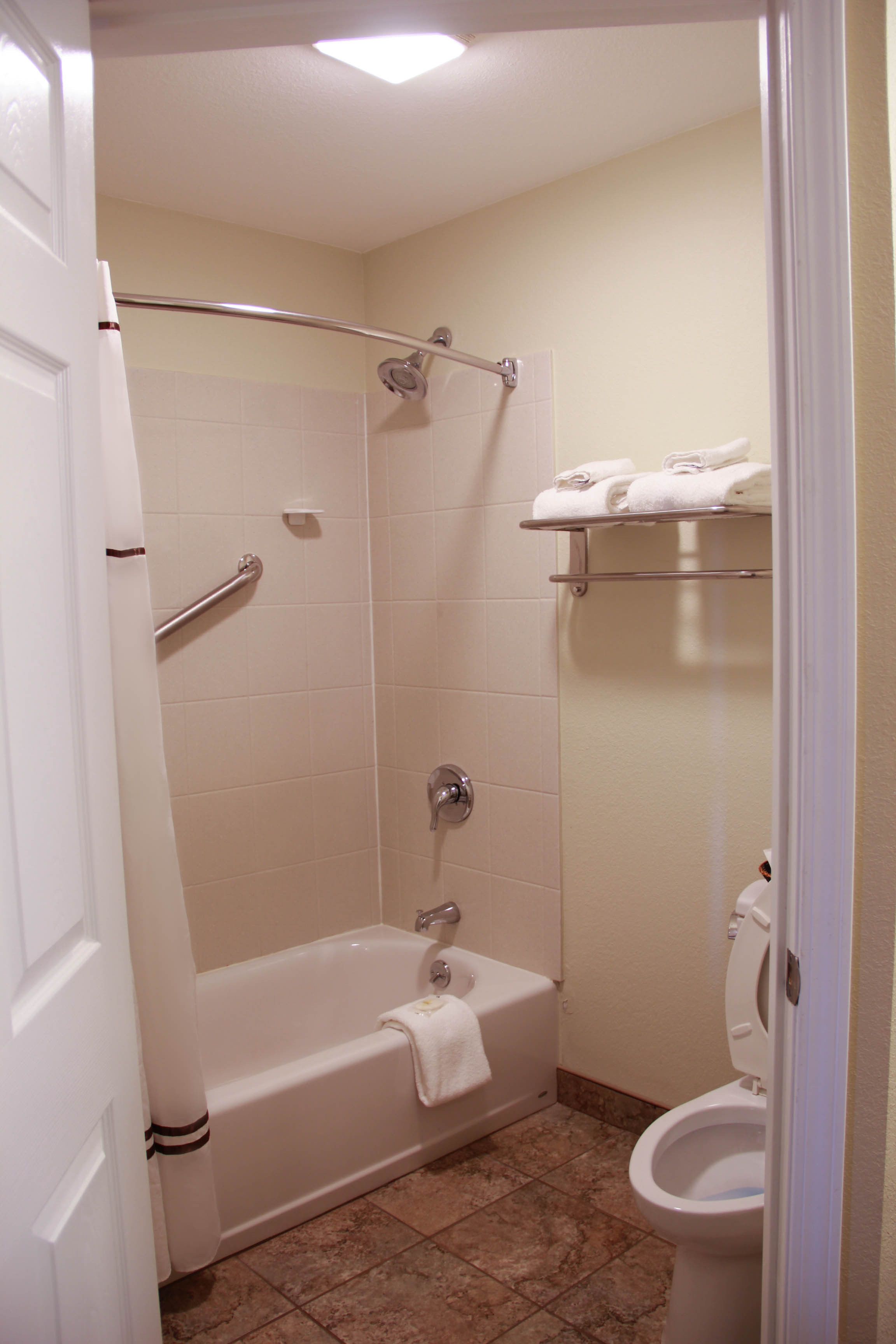 A bathroom with a bathtub, shower, toilet, and a towel rack.