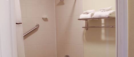 A bathroom with a bathtub, shower, toilet, and a towel rack.