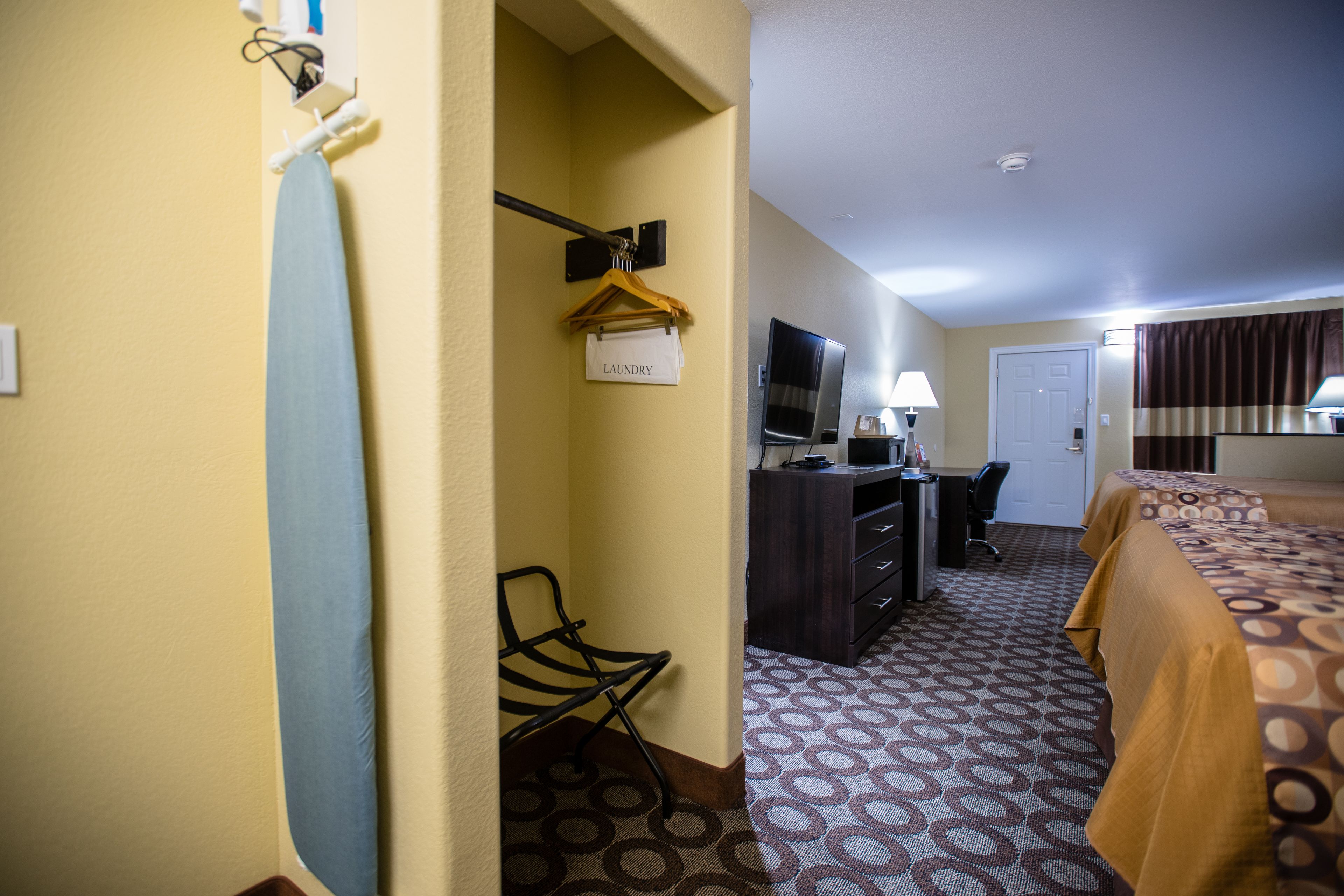 Una habitación de hotel con una cama, un escritorio con una computadora, un televisor y una silla.