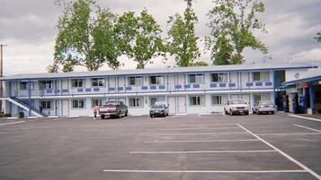 Un motel de dos pisos, un estacionamiento y varios coches aparcados.
