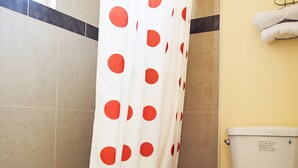 Un baño con bañera, inodoro y cortina de ducha con lunares rojos.