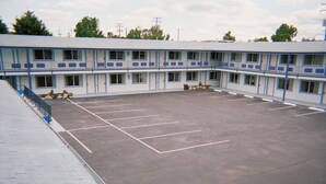 Un motel con un amplio estacionamiento y varias habitaciones con balcón.
