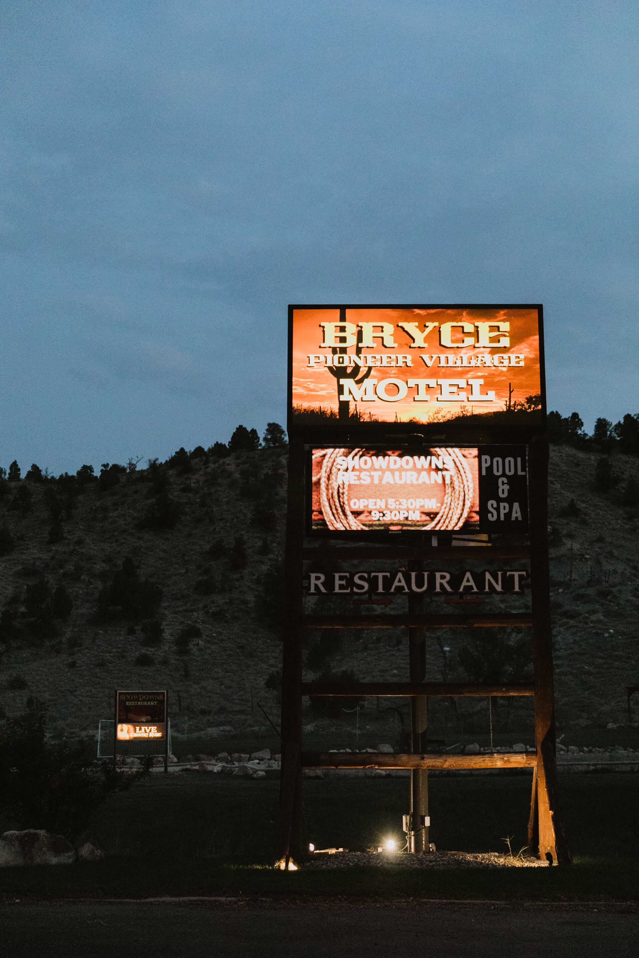 Ein Schild eines Motels mit der Aufschrift 'Bryce Pioneer Village Motel' und 'Showdowns Restaurant'.