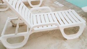 A swimming pool with white lounge chairs and a brick wall in the background. - Bryce Pioneer Village (Tropic)