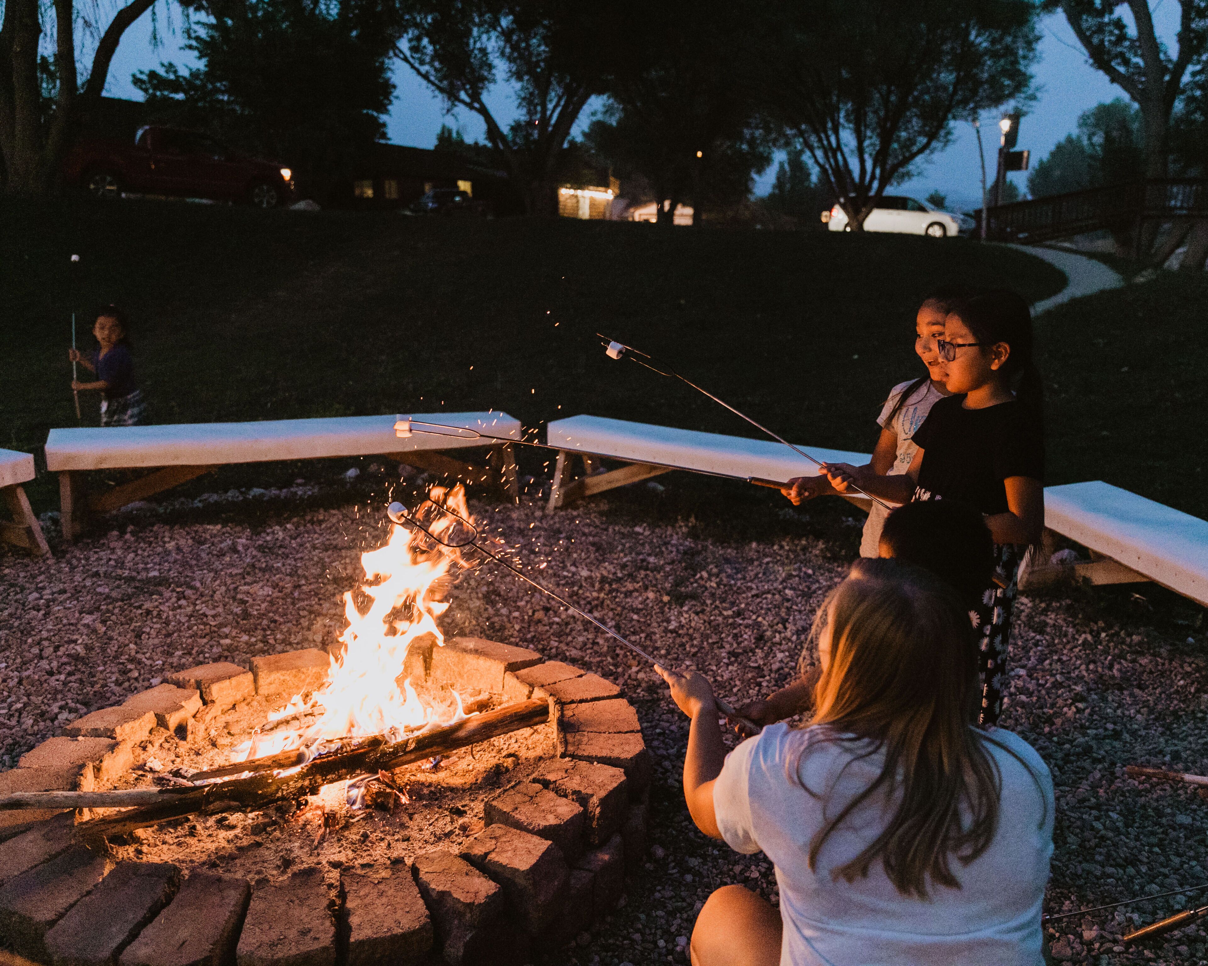 A campfire with people roasting marshmallows.