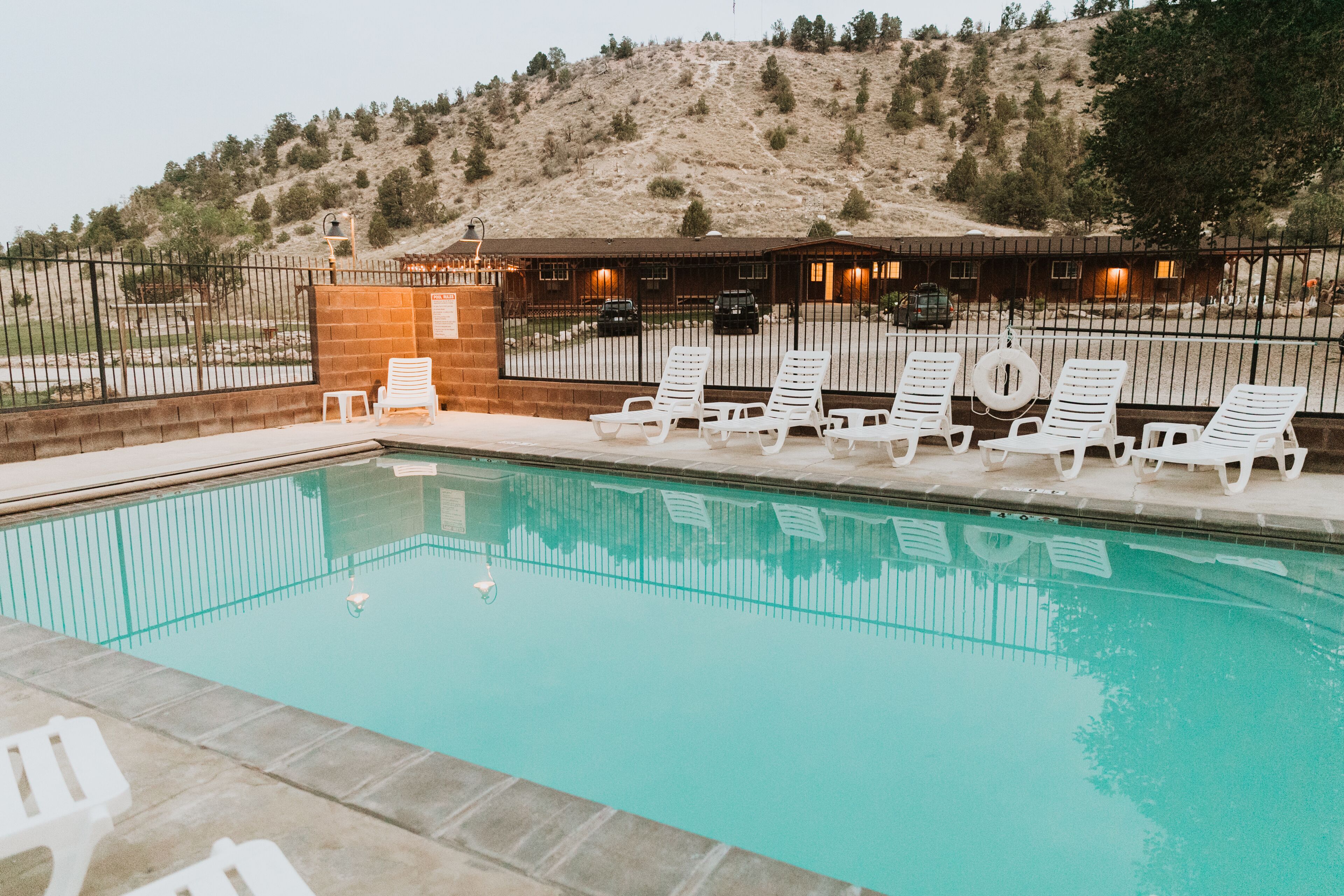 A swimming pool with white lounge chairs and a building in the background.