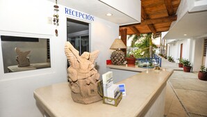 Un mostrador de recepción con una escultura de piedra, una lámpara y un letrero que dice "RECEPCIÓN".