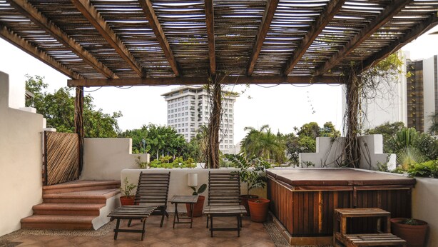 Una terraza en la azotea con muebles de madera, un jacuzzi y plantas en macetas.
