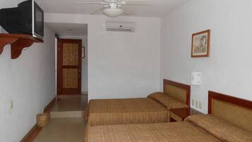 A room with two beds, a ceiling fan, an air conditioning unit, a television on a shelf, and a framed picture on the wall.