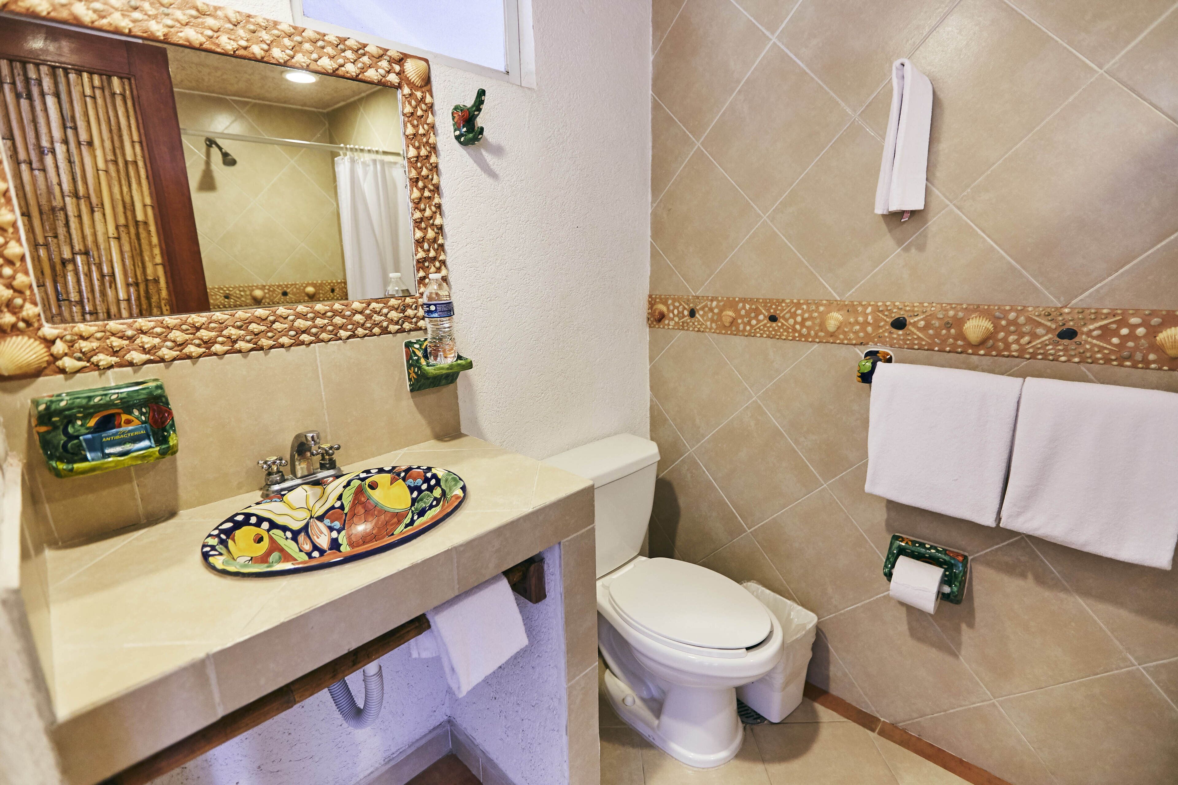 A bathroom with a sink, toilet, and a mirror with a decorative border.
