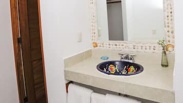 Un baño con puerta de madera, un lavamanos con espejo decorativo y dos toallas blancas.