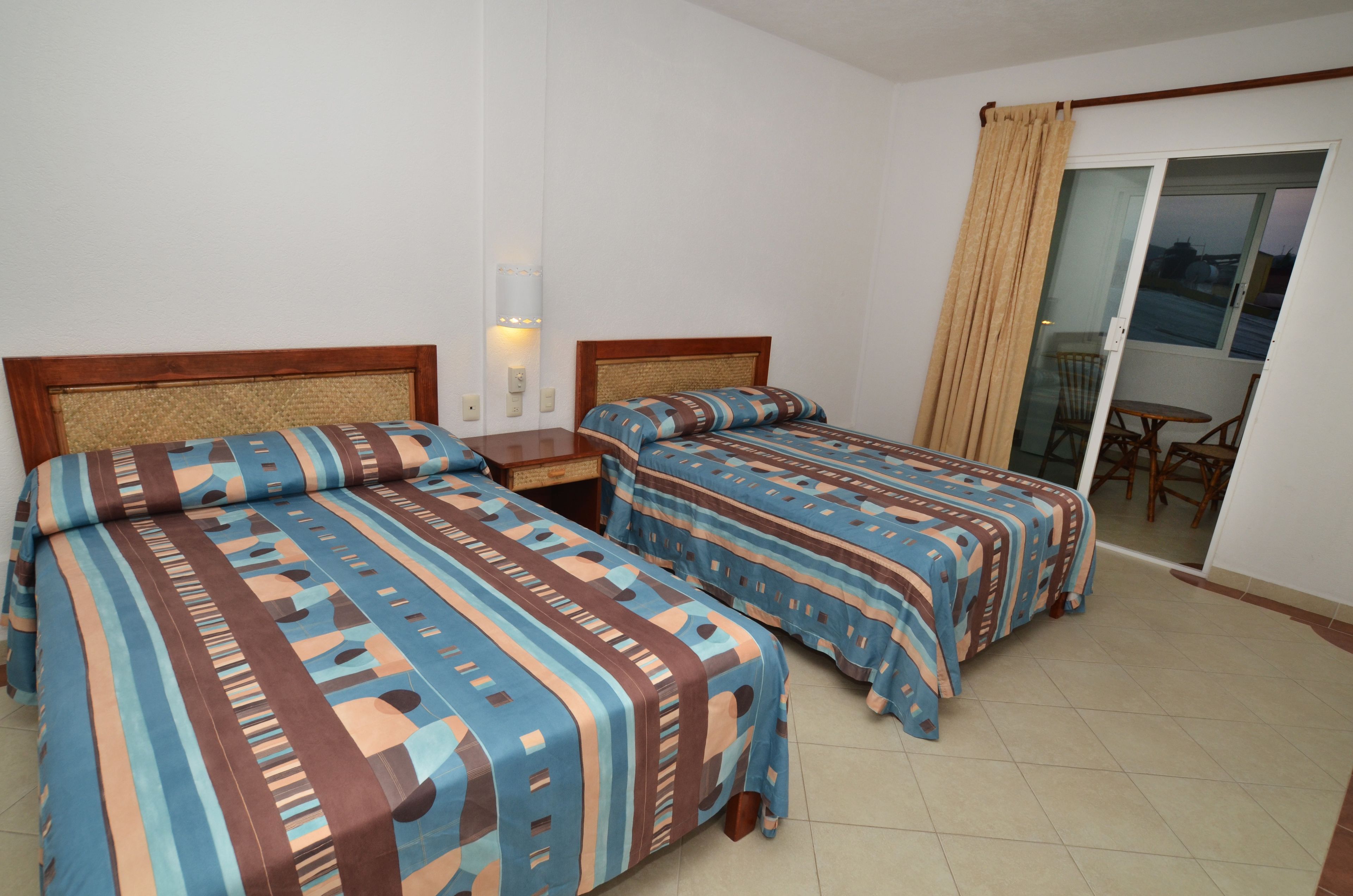 Una habitación de hotel con dos camas, una mesita pequeña y una silla.