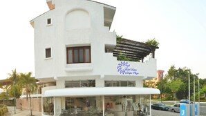 Un hotel moderno con fachada blanca, entrada cubierta y una señalización visible.