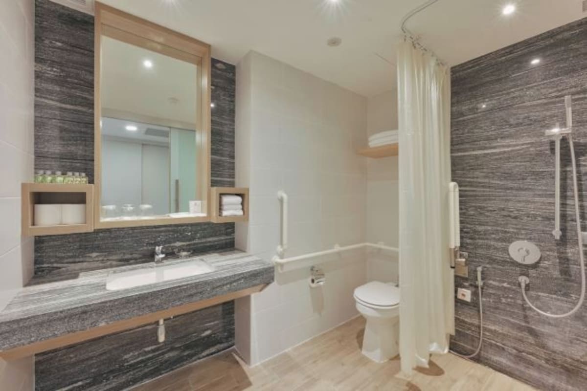 A modern bathroom with a marble sink, a toilet, and a shower area.
