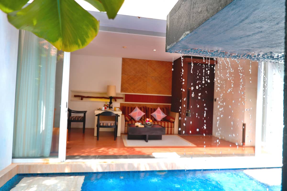 A modern living room with a sofa, coffee table, and a view of a swimming pool.