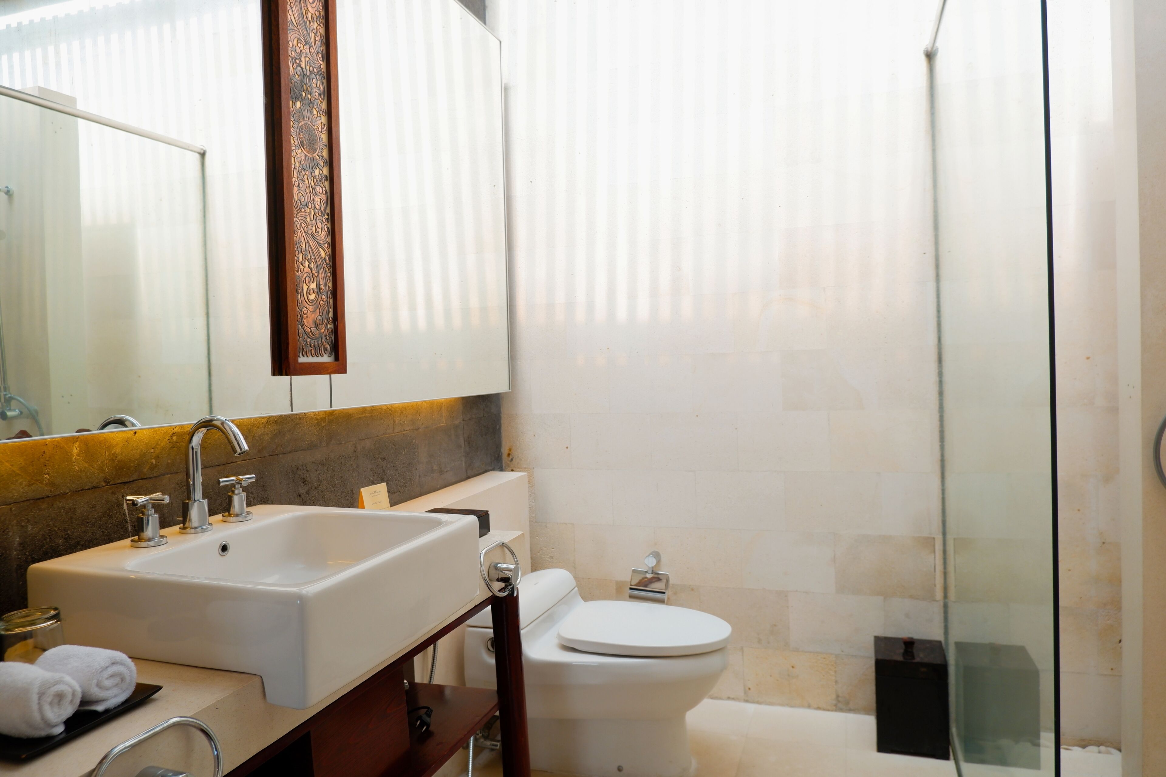 Une salle de bain équipée d’un lavabo, d’un miroir, de toilettes et d’une douche à parois en verre.