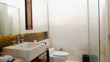 Une salle de bain équipée d’un lavabo, d’un miroir, de toilettes et d’une douche à parois en verre.