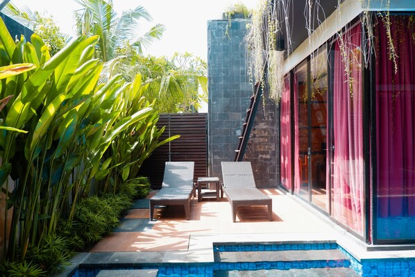 Un patio con dos sillones de mimbre, una mesita y una piscina.