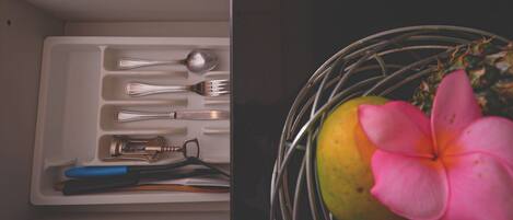 A drawer with utensils and a flower vase.