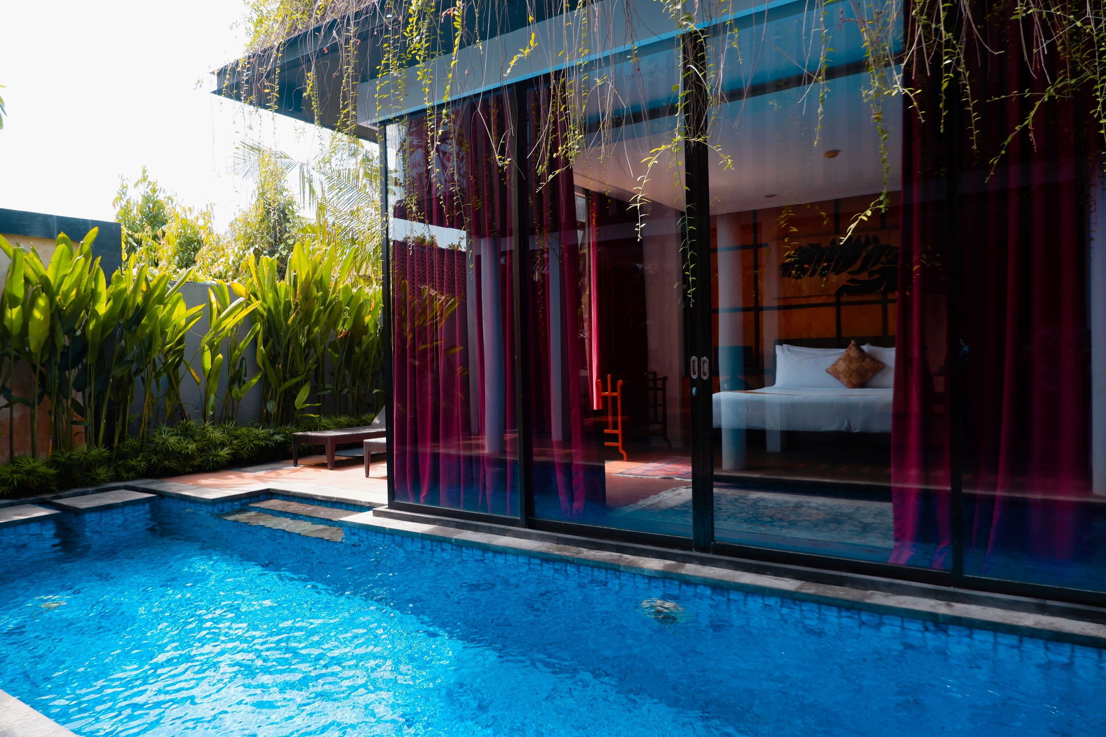 Habitación de hotel moderna con un ventanal grande, una cama y vista a una piscina.