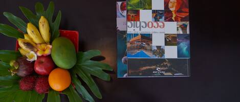 Uma mesa com uma composição de frutas e um livro intitulado 'ECOLOGICAL'.