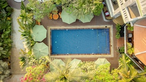 An aerial view of a swimming pool surrounded by lush greenery and outdoor seating. - Reveal Courtyard in Reveal Angkor (Siem Reap)