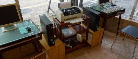 Una oficina pequeña con un ordenador de escritorio, una impresora y una silla.