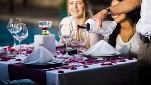 Una tavola imbandita per un pasto, con calici di vino, una torta e petali di rosa.