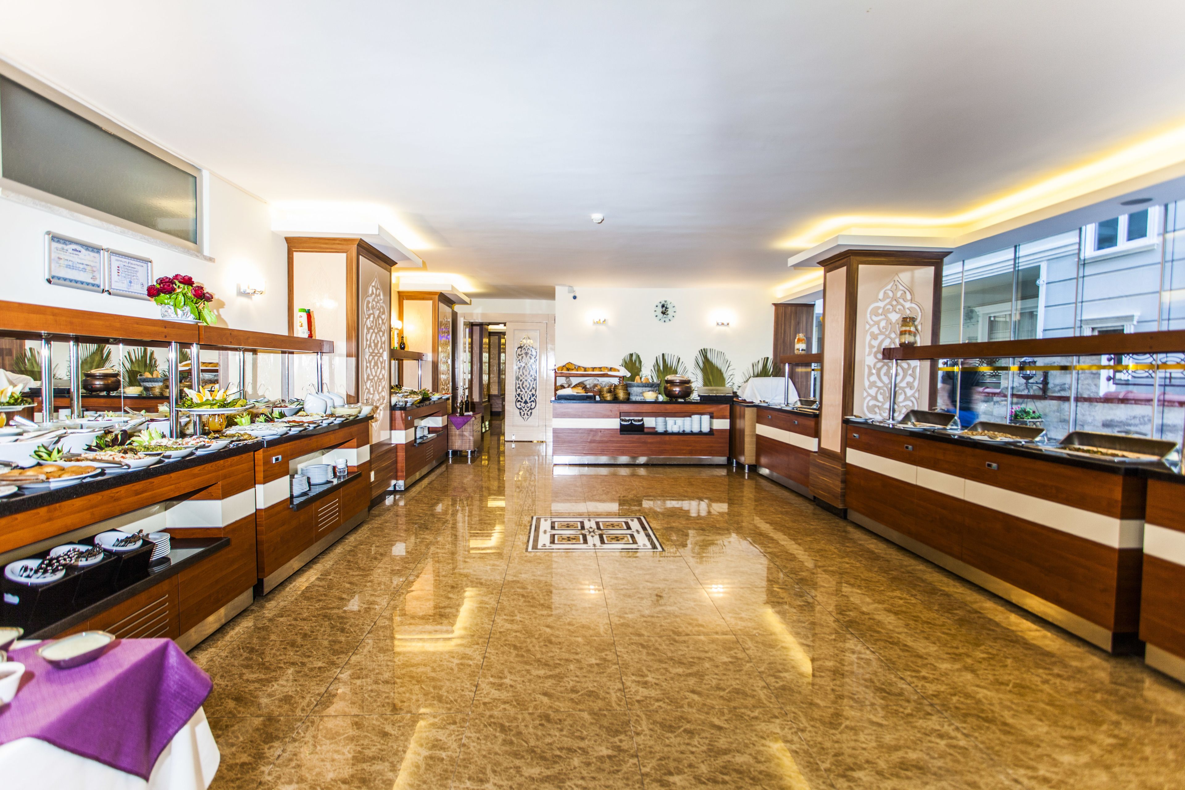 A buffet area with multiple food stations, a reception desk, and a decorative wall with a clock.