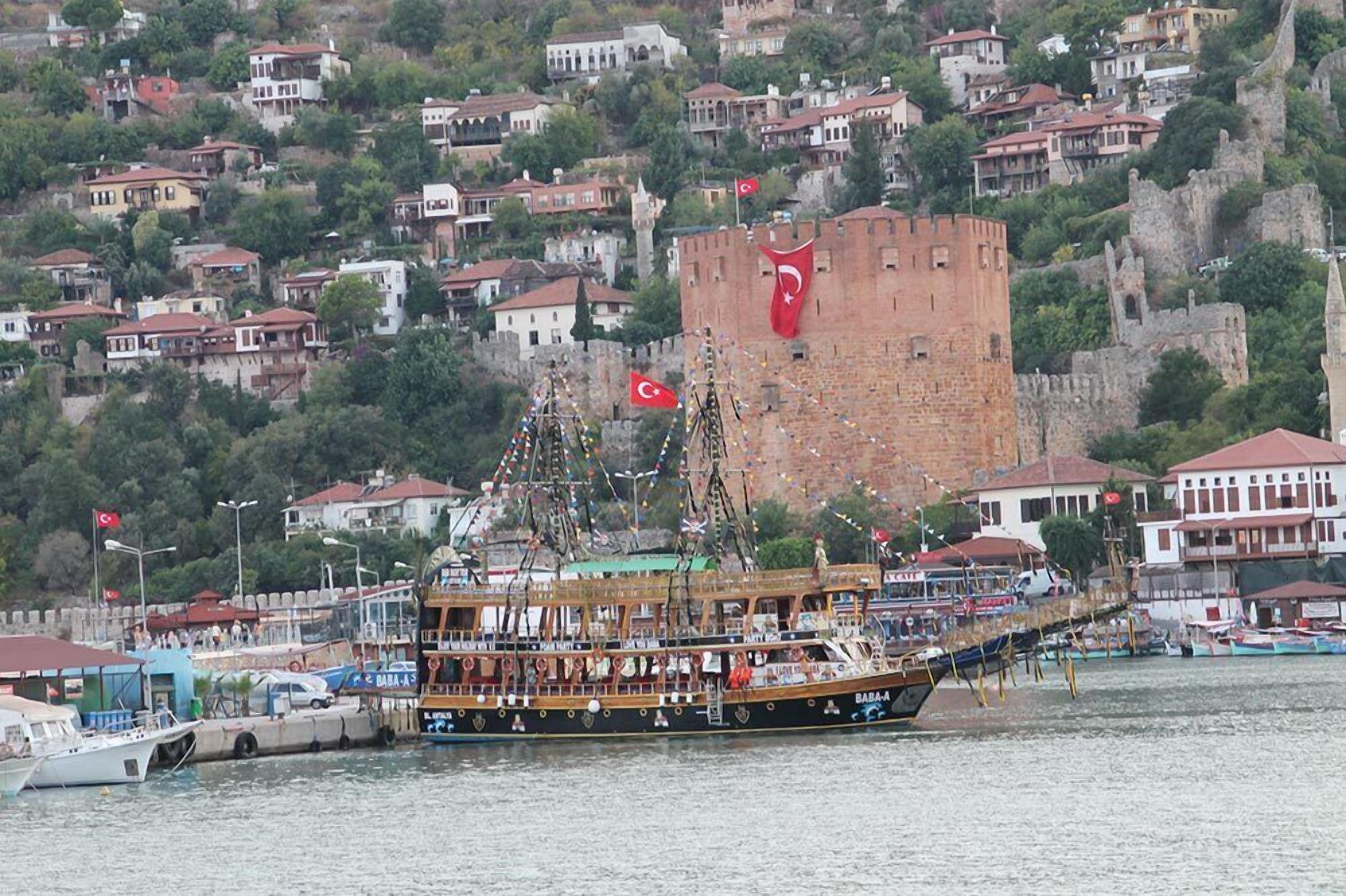 A traditional wooden boat docked at a harbor with a castle in the background.