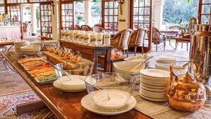 A buffet setup with various food items and a copper teapot. - Ilala Lodge Hotel (Victoria Falls)