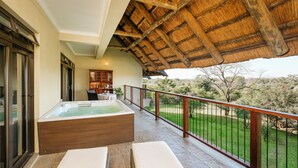 A balcony with a hot tub, lounge chairs, and a view of the surrounding landscape. - Ilala Lodge Hotel (Victoria Falls)