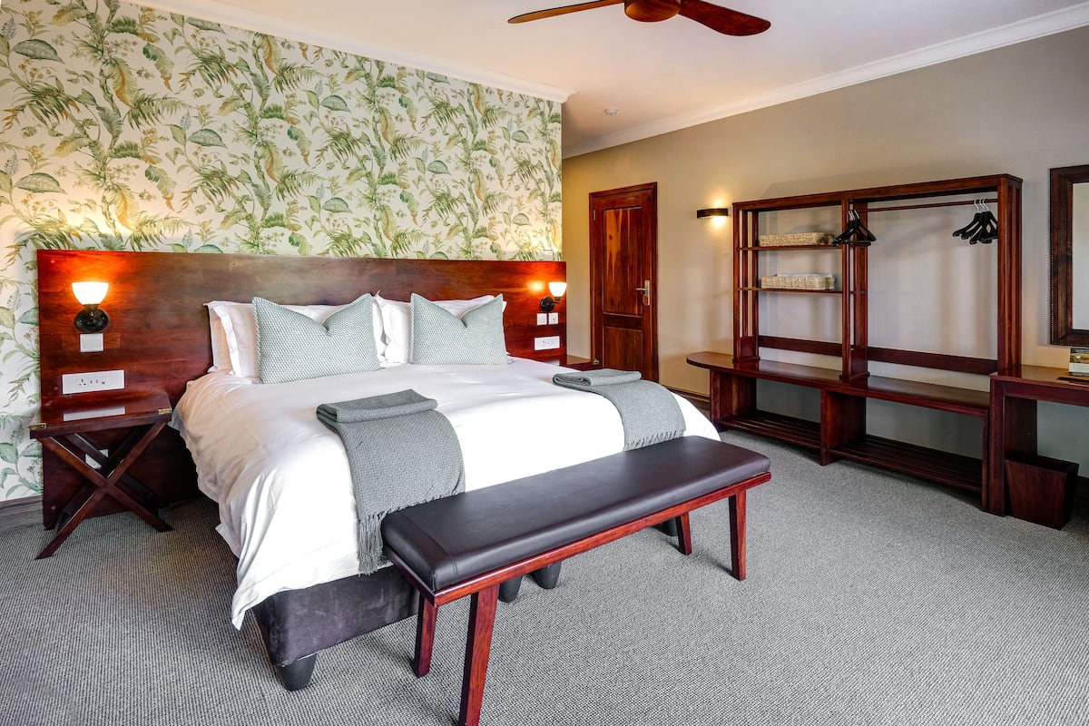 A neatly arranged bedroom with a large bed, bedside tables, a bench, and a wardrobe.