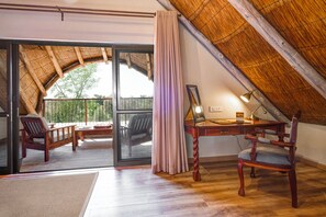 A room with a sloped ceiling, a desk with a lamp, and two chairs.