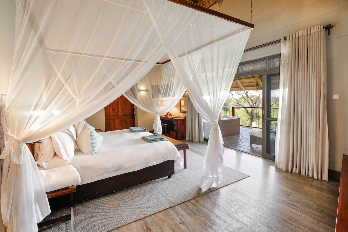 A spacious bedroom with a large bed, a wooden headboard, and a canopy.