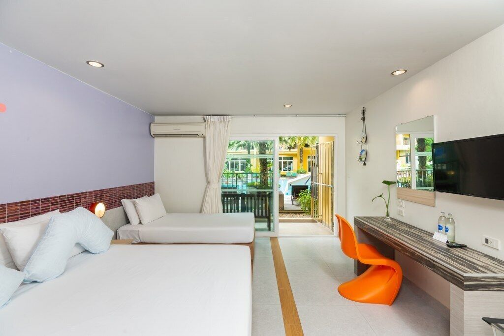 Una habitación de hotel con cama, escritorio con televisor y vista al exterior.