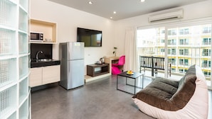 A modern apartment with a kitchen, dining area, and living room. It includes a flat-screen TV, a refrigerator, a dining table, and a sofa. - Grand Bella Hotel (Pattaya)