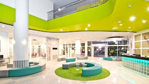 A spacious lobby with a central seating area, a staircase, and a reception desk. - Grand Bella Hotel (Pattaya)