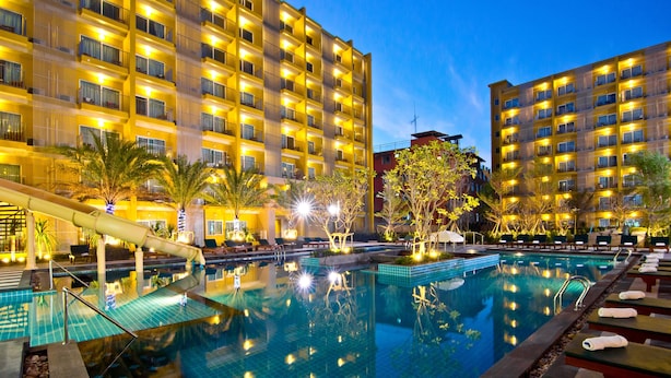 A hotel with a large outdoor swimming pool, multiple balconies, and well-lit surroundings. - Grand Bella Hotel (Pattaya)