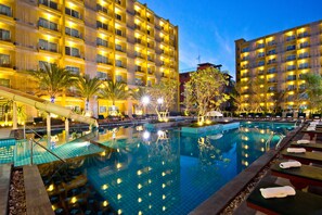 A hotel with a large outdoor swimming pool, multiple balconies, and well-lit surroundings. - Grand Bella Hotel (Pattaya)