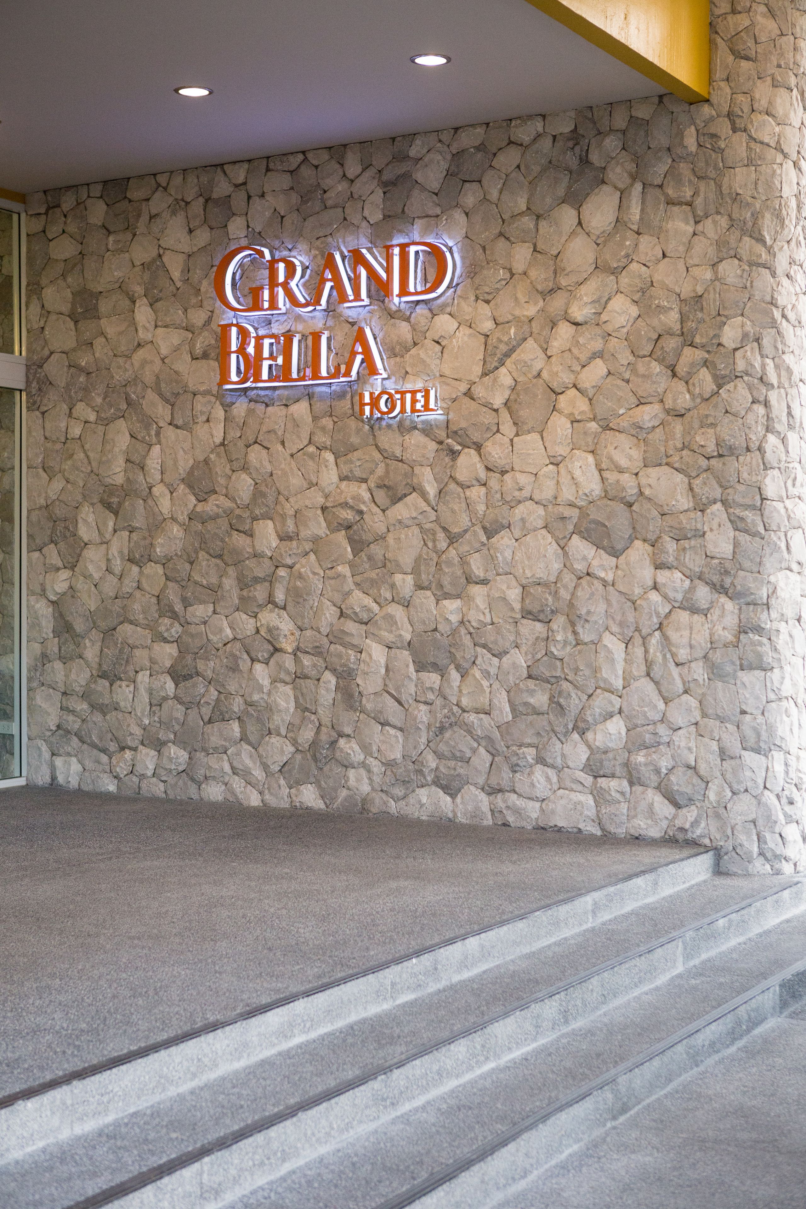 Un mur de pierre sur lequel est apposée une enseigne indiquant l’hôtel Grand Bella.