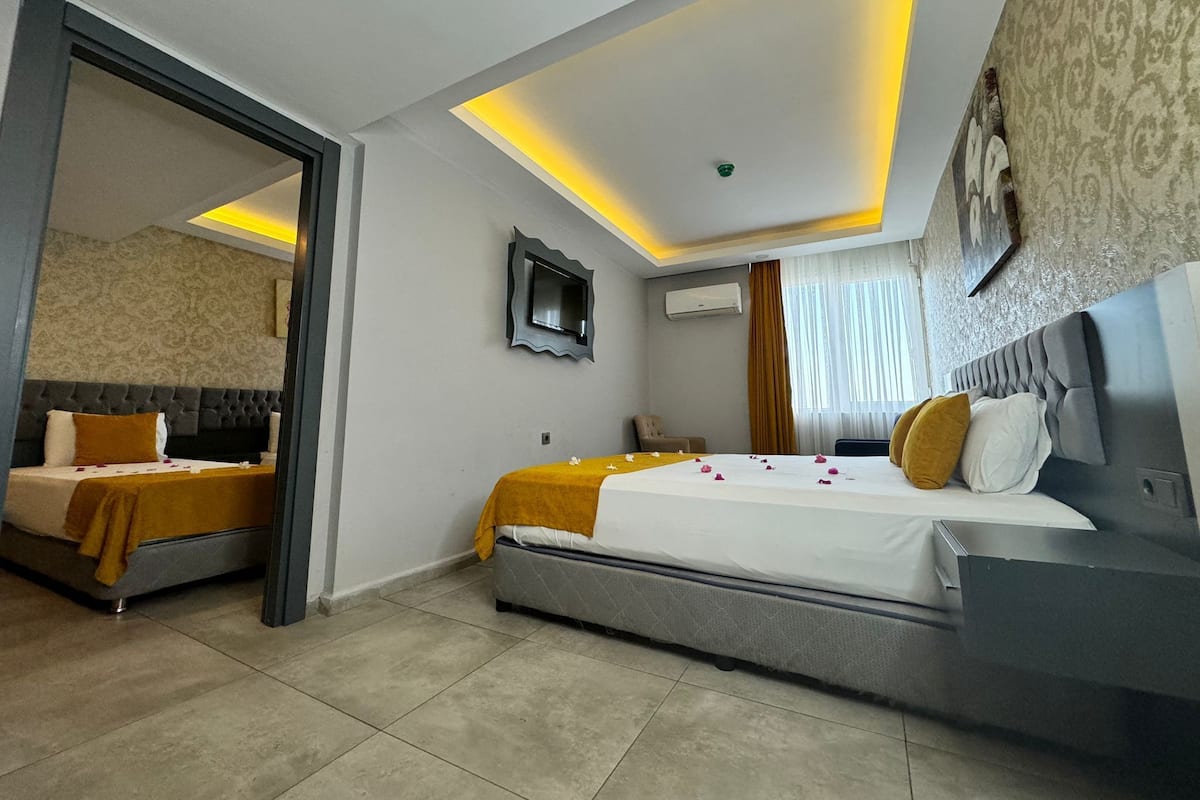 A hotel room with a large bed, a desk, a mirror, and a television.