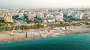 Vue aérienne d’une ville côtière avec une plage où se trouve un hôtel appelé « ERDEM HOTEL ».