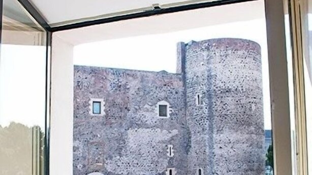 A room with a view of a stone building with multiple windows and a door.