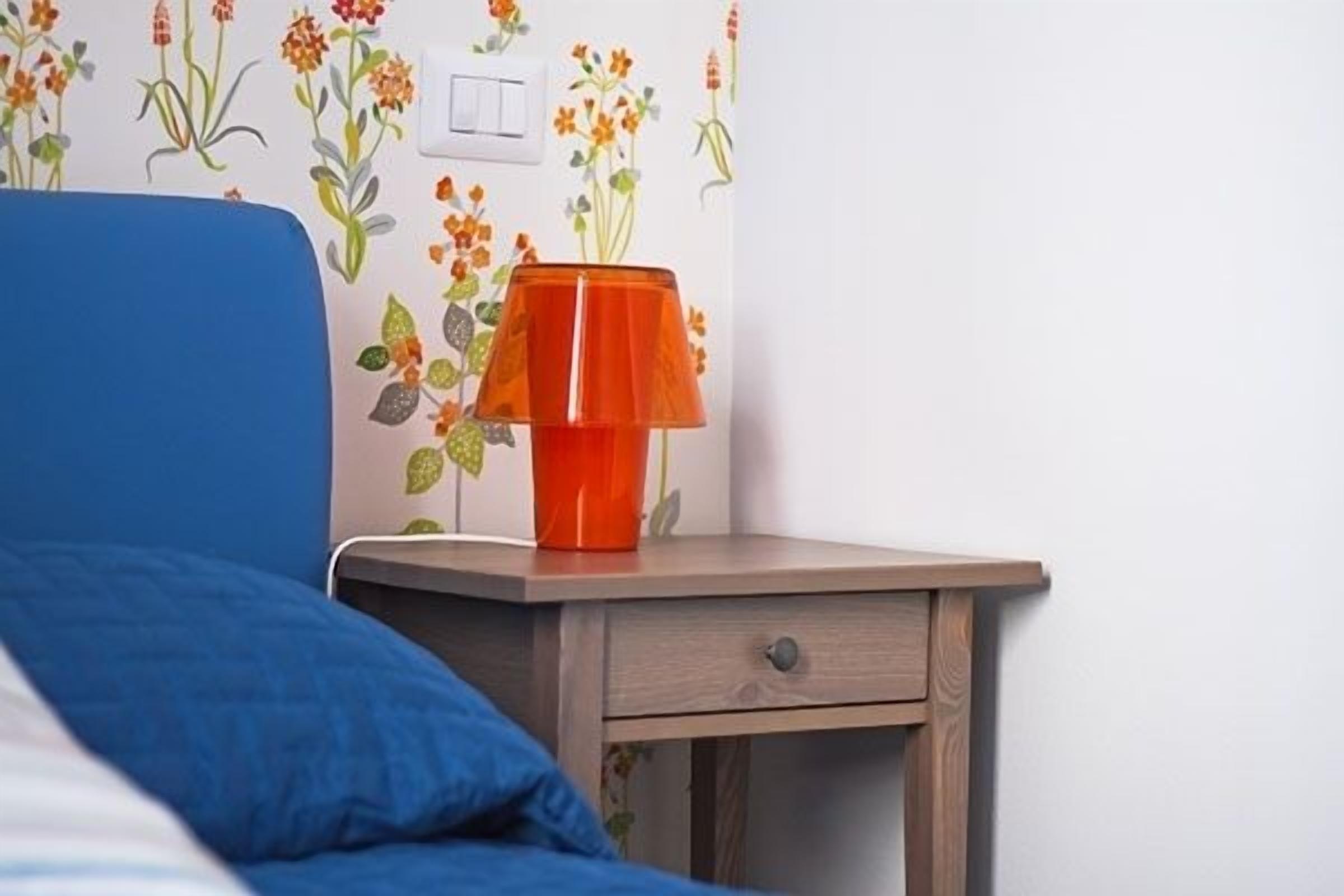Una camera da letto con un letto, un comodino e una lampada.
