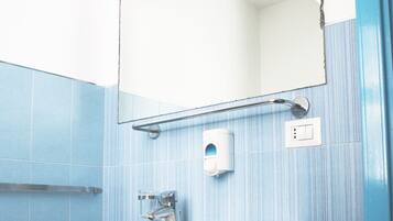 Un baño con lavamanos blanco, un espejo y paredes de azulejos azules.